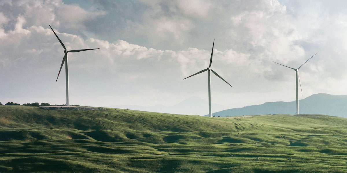 Windmills sitting above rolling green hills to help power green hydrogen.